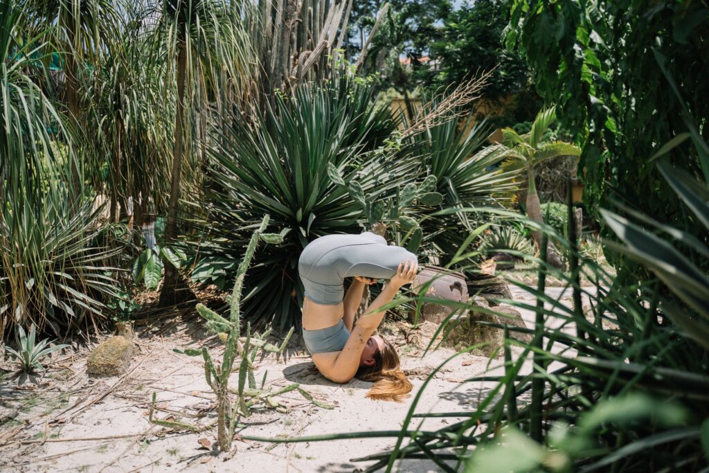 Kerala Wellness Practices: A Journey to Natural Health, Inner Peace, and Holistic Living A woman performing a headstand yoga pose outdoors in a vibrant, lush garden setting.