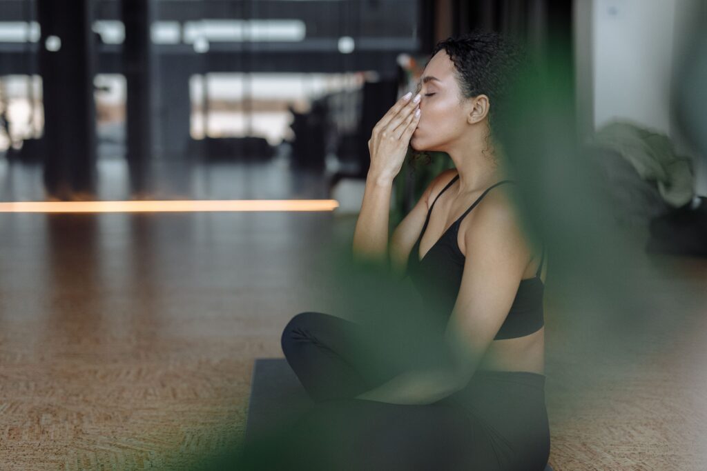 Breathing Techniques in Yoga: The Foundation of Physical and Mental Well-Being Peaceful woman practicing yoga indoors with eyes closed, focusing on breathing and relaxation.