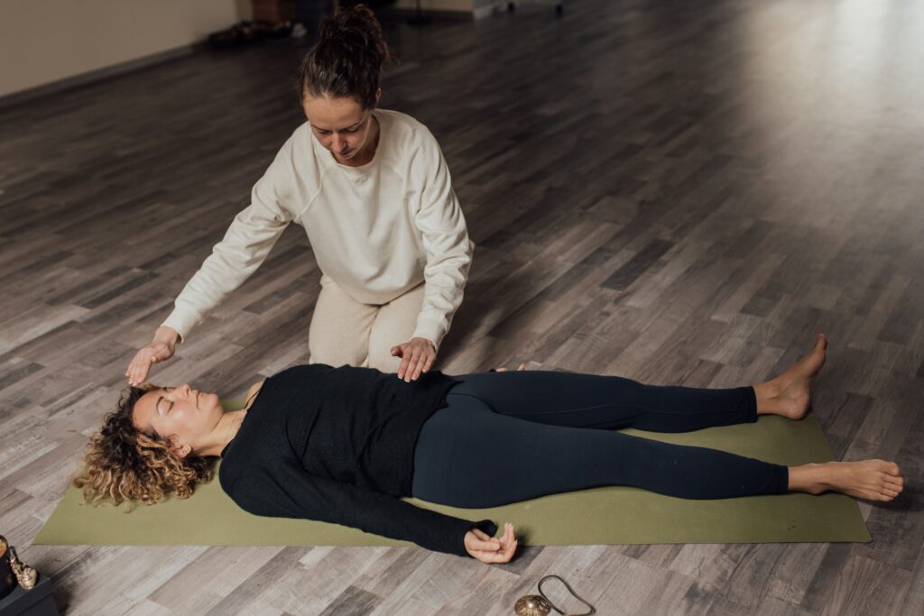 Kerala Wellness Practices: A Journey to Natural Health, Inner Peace, and Holistic Living Energy therapist healing barefoot female with closed eyes during meditation practice on floor in sunlight